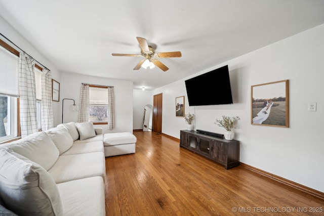 living area featuring ceiling fan, baseboards, and wood finished floors