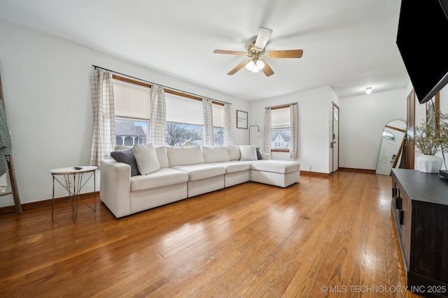 unfurnished living room with ceiling fan, light wood-style flooring, and baseboards