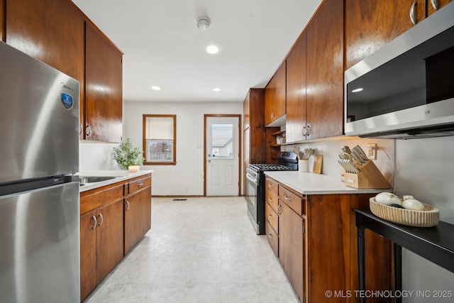 kitchen with tasteful backsplash, baseboards, appliances with stainless steel finishes, light countertops, and recessed lighting