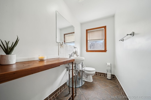 bathroom with toilet, baseboards, a sink, and tile patterned floors