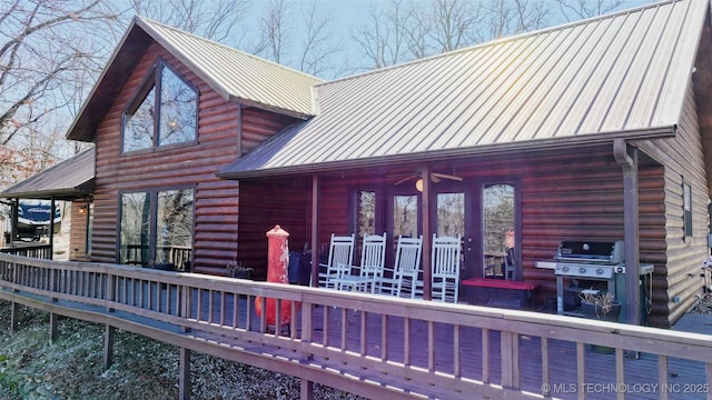 back of house with a ceiling fan, metal roof, and a wooden deck