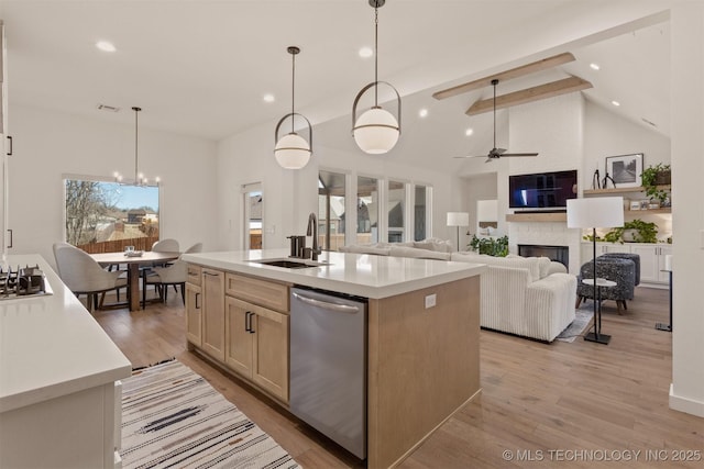 kitchen with stainless steel appliances, a fireplace, a sink, light countertops, and light wood-type flooring