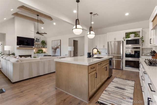 kitchen featuring visible vents, decorative backsplash, lofted ceiling with beams, stainless steel appliances, and a sink