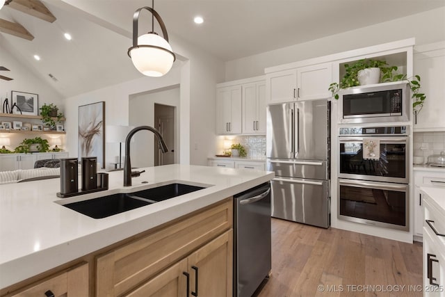 kitchen featuring light wood-style flooring, stainless steel appliances, a sink, and light countertops