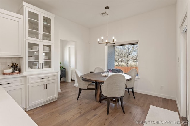 dining space featuring light wood-style floors, visible vents, baseboards, and an inviting chandelier