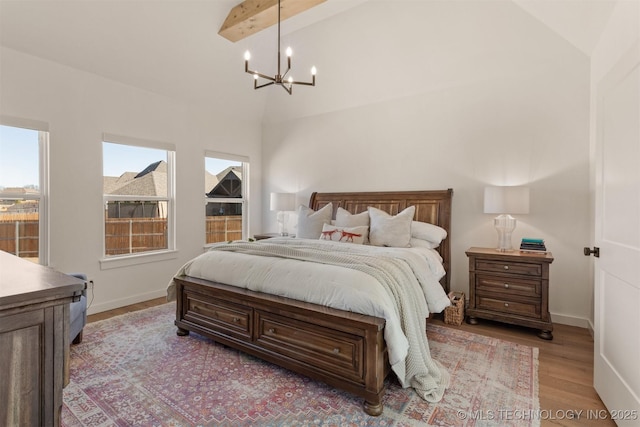 bedroom featuring light wood-style floors, a notable chandelier, vaulted ceiling with beams, and baseboards