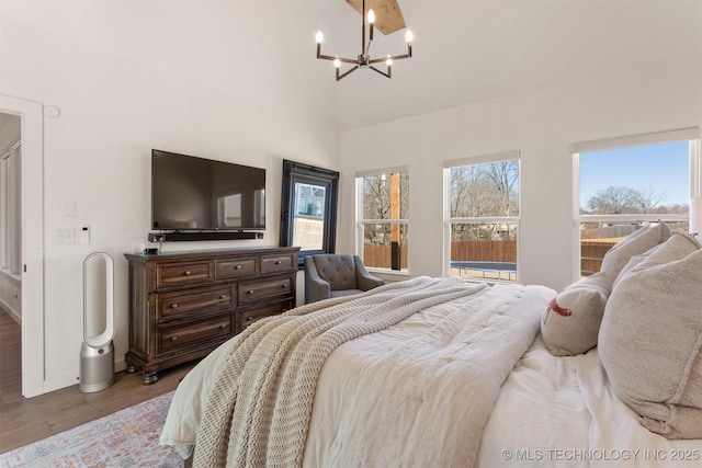 bedroom featuring baseboards, wood finished floors, and a notable chandelier