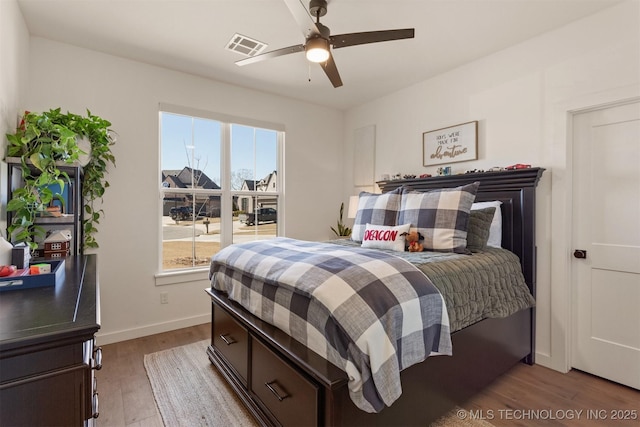 bedroom with ceiling fan, wood finished floors, visible vents, and baseboards