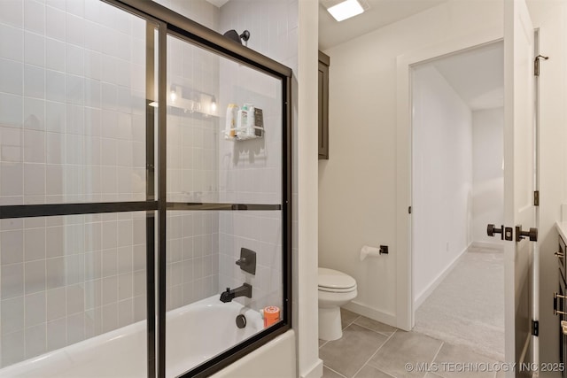 bathroom featuring tile patterned floors, baseboards, toilet, and bath / shower combo with glass door