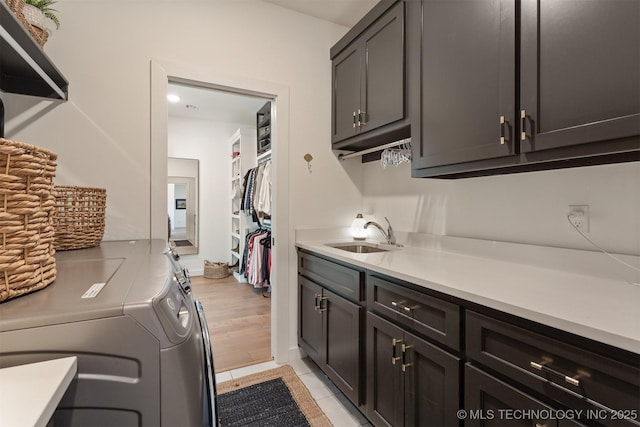 laundry room featuring cabinet space, light tile patterned floors, a sink, and washing machine and clothes dryer