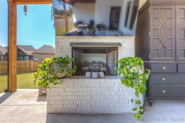 view of patio featuring a garage, an outdoor fireplace, fence, and area for grilling