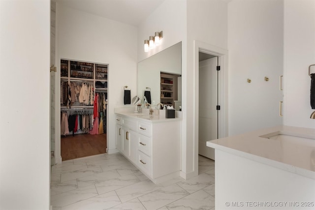 full bathroom with marble finish floor, a spacious closet, and vanity