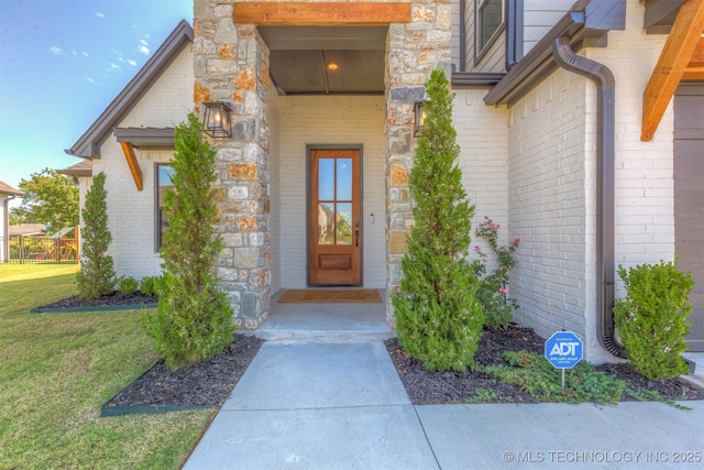 doorway to property with stone siding, brick siding, and a lawn