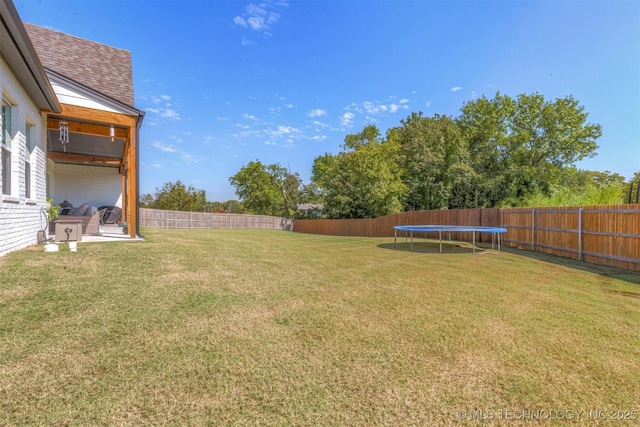 view of yard with a trampoline and a fenced backyard