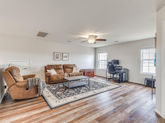 living area with baseboards, wood finished floors, visible vents, and a ceiling fan