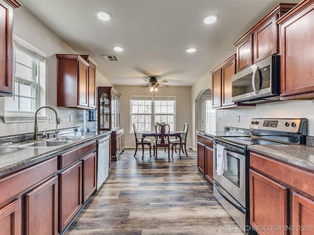 kitchen featuring visible vents, dark wood finished floors, dark countertops, stainless steel appliances, and a sink