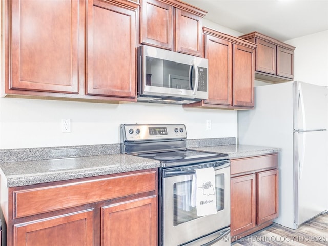 kitchen featuring appliances with stainless steel finishes, light countertops, brown cabinetry, and light wood-style flooring