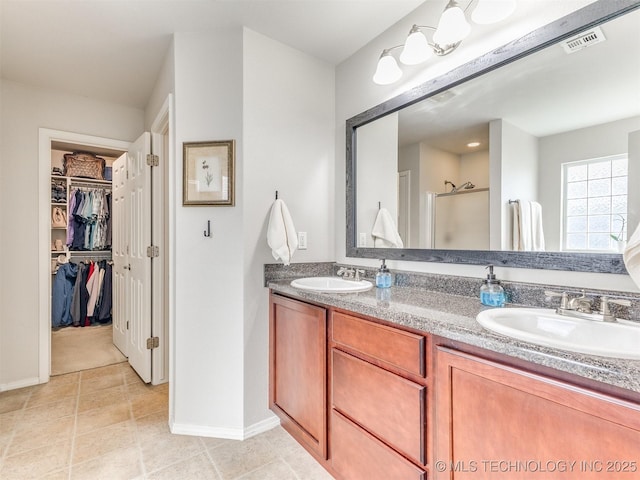 bathroom with double vanity, visible vents, a spacious closet, a sink, and a shower stall