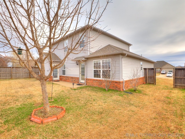 exterior space featuring a yard, brick siding, and fence