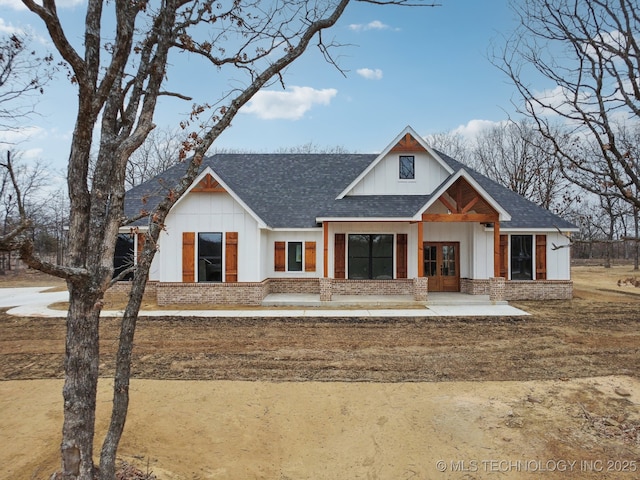 modern farmhouse style home featuring a shingled roof, french doors, brick siding, and board and batten siding