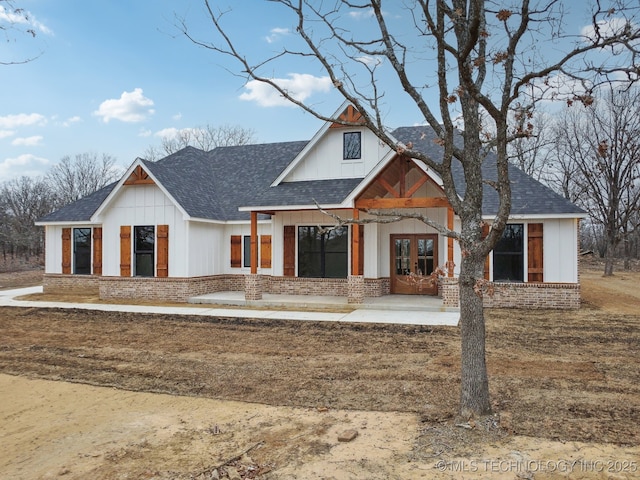 modern inspired farmhouse featuring french doors, brick siding, and a shingled roof