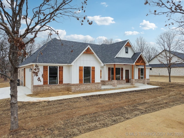 modern farmhouse featuring an attached garage, brick siding, board and batten siding, and a shingled roof