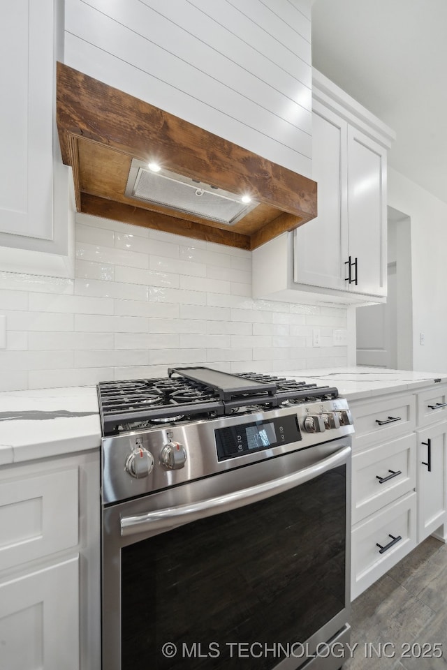 kitchen with tasteful backsplash, white cabinets, dark wood-type flooring, and gas stove