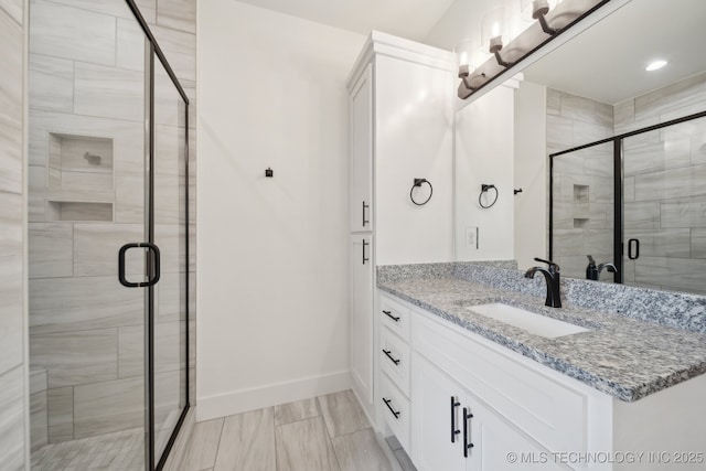 bathroom with a stall shower, vanity, and baseboards