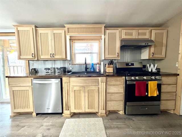 kitchen with light brown cabinets, under cabinet range hood, a sink, appliances with stainless steel finishes, and light wood-type flooring