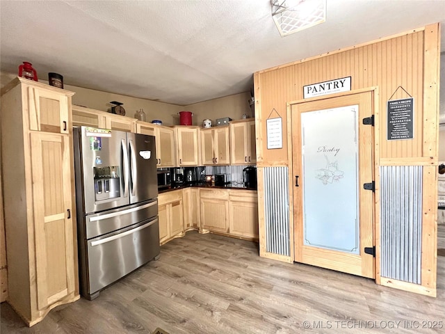 kitchen featuring wooden walls, stainless steel fridge with ice dispenser, dark countertops, wood finished floors, and light brown cabinetry