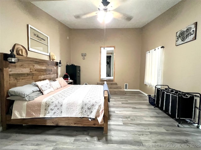 bedroom with a ceiling fan, baseboards, and wood finished floors