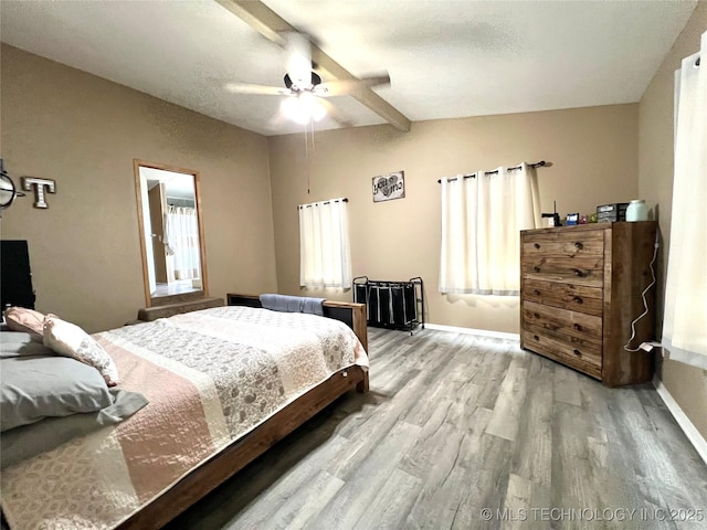 bedroom with vaulted ceiling with beams, wood finished floors, a ceiling fan, and baseboards