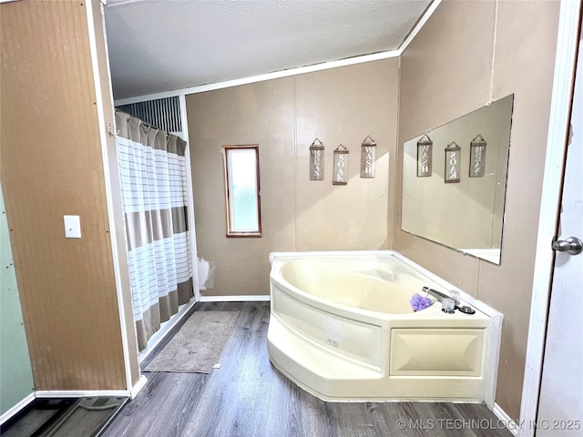 full bath featuring baseboards, crown molding, a bath, and wood finished floors