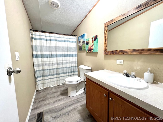 bathroom with visible vents, toilet, vanity, a textured ceiling, and wood finished floors