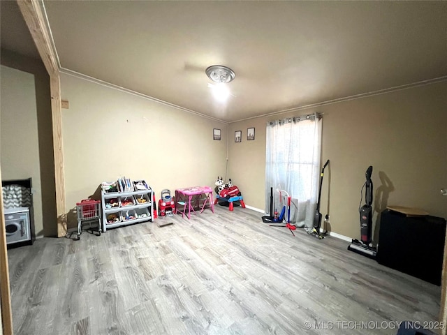 rec room with crown molding, baseboards, and wood finished floors