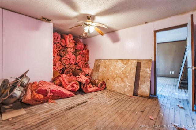 bedroom with a textured ceiling, wood-type flooring, visible vents, and a ceiling fan