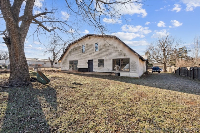 rear view of house featuring fence and a gambrel roof