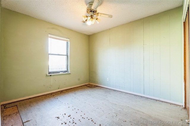 spare room with a textured ceiling, ceiling fan, and baseboards