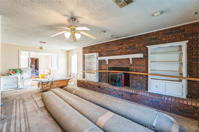 living room with a textured ceiling, ceiling fan, brick wall, and visible vents