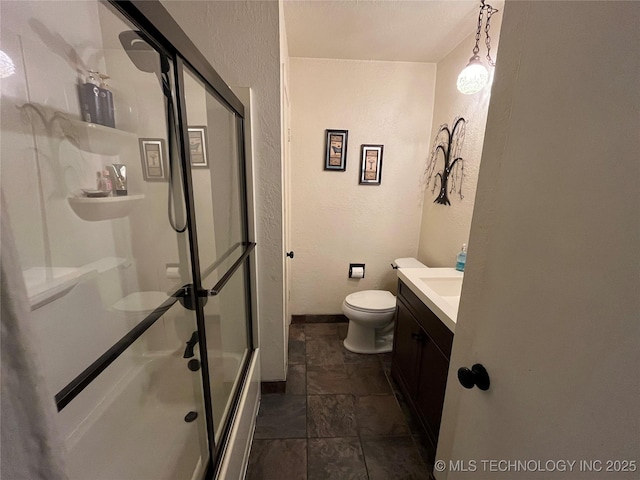 bathroom with toilet, vanity, baseboards, and a textured wall