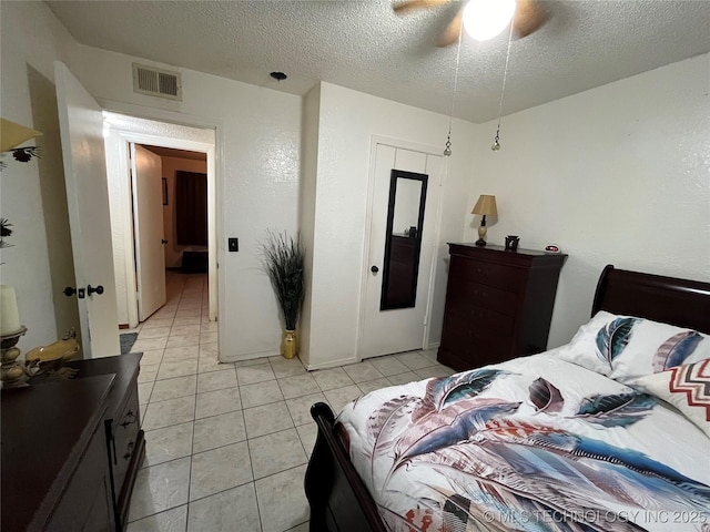 bedroom featuring light tile patterned floors, a ceiling fan, visible vents, and a textured ceiling