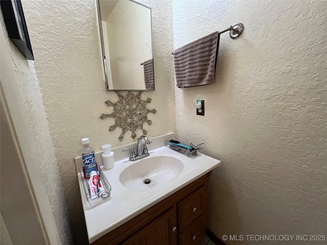 bathroom with a textured wall and vanity