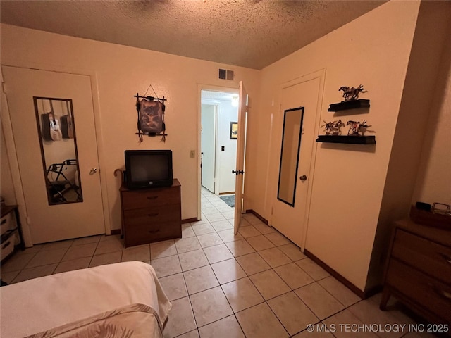 bedroom featuring visible vents, a textured ceiling, and light tile patterned flooring