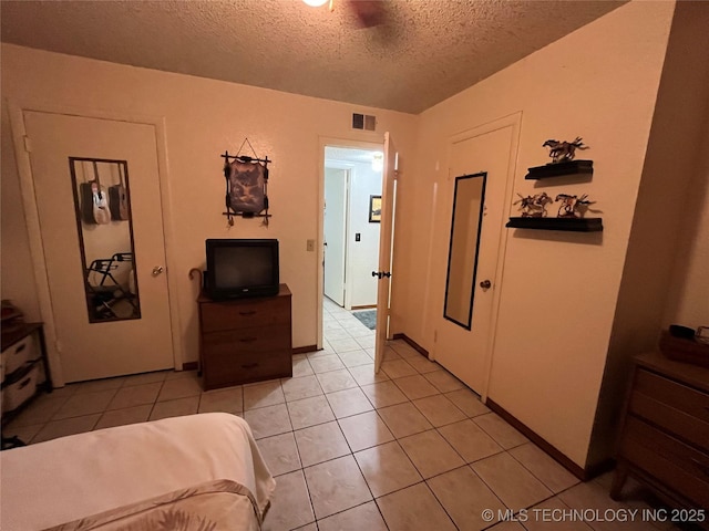 bedroom featuring visible vents, a textured ceiling, and light tile patterned floors