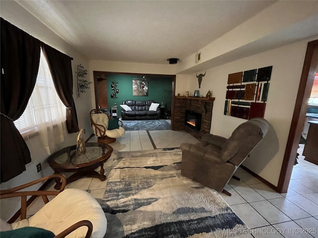 tiled living area featuring a lit fireplace and baseboards