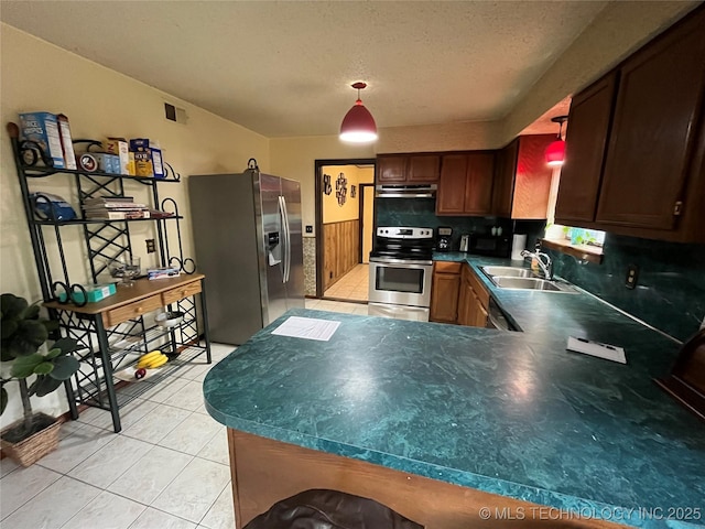 kitchen with light tile patterned floors, under cabinet range hood, a sink, appliances with stainless steel finishes, and backsplash