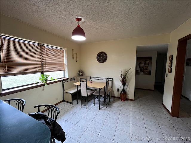 dining room featuring a textured ceiling, baseboards, and light tile patterned floors