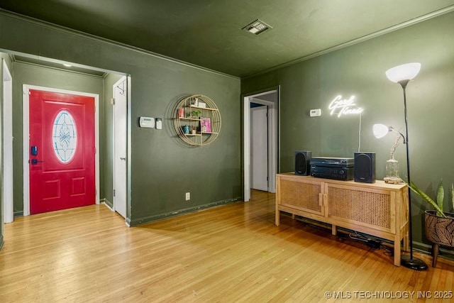 home office with ornamental molding, visible vents, and wood finished floors