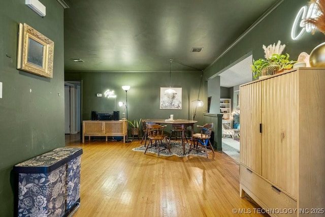 dining space featuring visible vents, ornamental molding, and wood finished floors