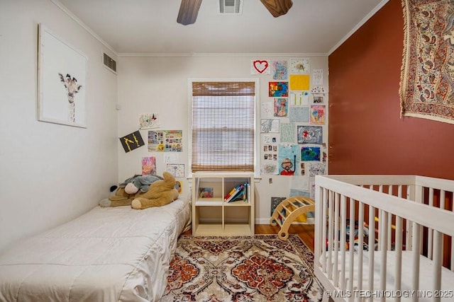 bedroom featuring a ceiling fan, visible vents, wood finished floors, and ornamental molding